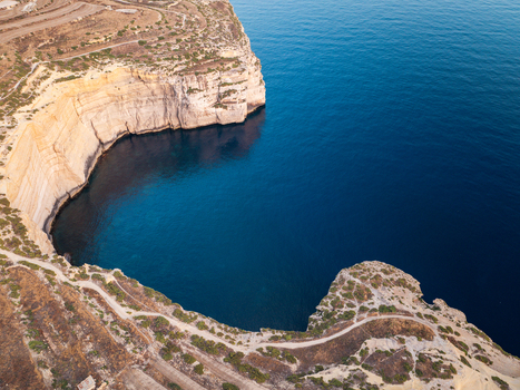 Aerial view of the rugged Sanap Cliffs plunging into the deep blue sea creating a mesmerizing contrast of earth and water Munxar Gozo Malta. Aerial view of the rugged Sanap Cliffs plunging into the deep blue sea creating a mesmerizing contrast of earth and water Munxar Gozo Malta.