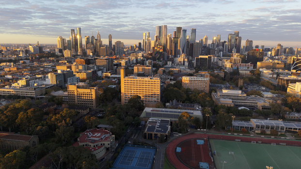 Aerial view of the Melbourne city skyline featuring modern skyscrapers and urban architecture in golden hour light with sports fields in the foreground Melbourne Victoria Australia.