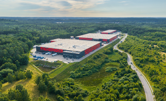 Aerial view of Gdansk Kowale Distribution Centre with red and black industrial buildings and loading docks surrounded by forest in Kowale Wojewodztwo pomorskie Poland. Aerial view of Gdansk Kowale Distribution Centre with red and black industrial buildings and loading docks surrounded by forest in Kowale Wojewodztwo pomorskie Poland.