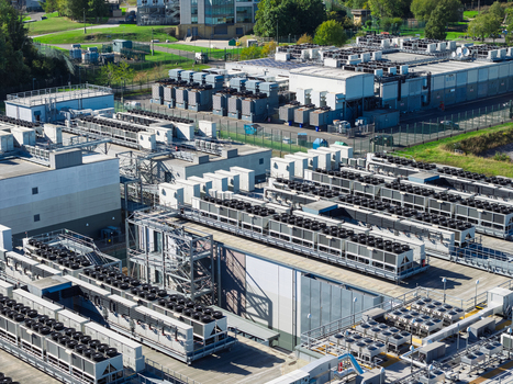 Aerial view of a large data center facility featuring rows of industrial cooling units and technical infrastructure in the United Kingdom.