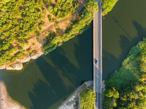 Aerial view of the Karaagach bridge crossing the river surrounded by lush green trees and rocky banks in Kiten Burgas Bulgaria. Aerial view of the Karaagach bridge crossing the river surrounded by lush green trees and rocky banks in Kiten Burgas Bulgaria.