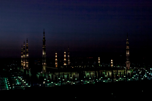 View of the illuminated minarets and architecture of Al Masjid e Nabawi at night in Madinah Al Madinah Province Saudi Arabia.