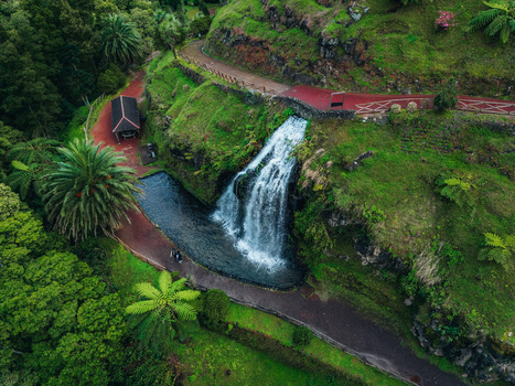 Aerial view of a majestic waterfall cascading into a serene pool framed by verdant foliage and winding paths Achada Açores Portugal. Aerial view of a majestic waterfall cascading into a serene pool framed by verdant foliage and winding paths Achada Açores Portugal.