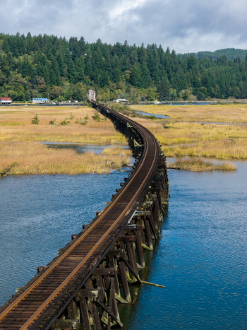 Aerial view of railroad tracks on the Coos Bay Rail Line running across tidal flats near Florence Oregon with open water marsh and coastal backwaters.