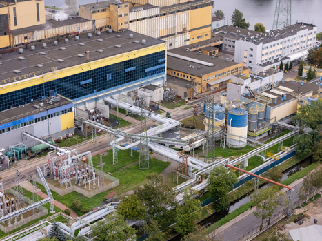 Aerial view of the coal fired power plant featuring industrial infrastructure cooling towers and complex piping systems surrounded by green spaces in Gdansk Poland. Aerial view of the coal fired power plant featuring industrial infrastructure cooling towers and complex piping systems surrounded by green spaces in Gdansk Poland.