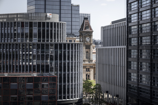 Aerial view of the historic Chamberlain Clock Tower framed by modern glass and steel office buildings in the city center of Birmingham England United Kingdom.