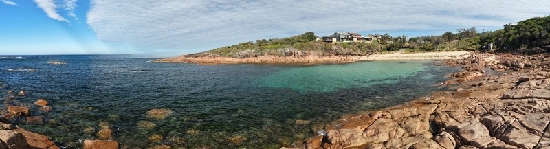 Aerial view of turquoise waters meet rugged reddish brown rocks and sandy beach under a sky streaked with light clouds Coogee New South Wales Australia. Aerial view of turquoise waters meet rugged reddish brown rocks and sandy beach under a sky streaked with light clouds Coogee New South Wales Australia.
