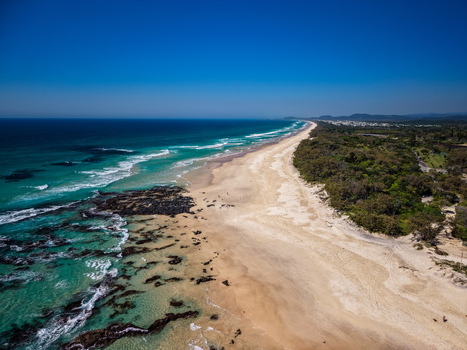 Aerial view of Cudgen Headland South Head featuring a sandy beach turquoise ocean waves crashing against rocky outcrops and lush coastal vegetation in Kingscliff New South Wales Australia. Aerial view of Cudgen Headland South Head featuring a sandy beach turquoise ocean waves crashing against rocky outcrops and lush coastal vegetation in Kingscliff New South Wales Australia.