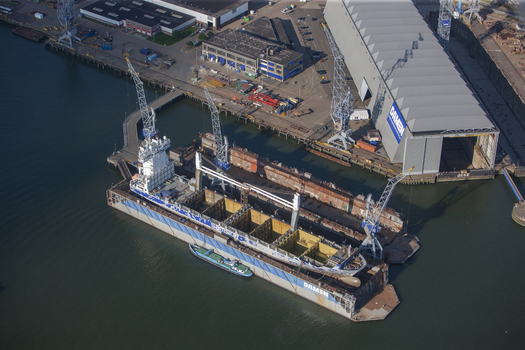 Rotterdam Netherlands 03 September 2014 Aerial view of Rotterdam Harbour showing a large cargo ship undergoing maintenance in a floating dry dock with industrial cranes and shipyard facilities. Rotterdam Netherlands 03 September 2014 Aerial view of Rotterdam Harbour showing a large cargo ship undergoing maintenance in a floating dry dock with industrial cranes and shipyard facilities.