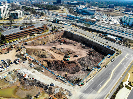 Reston Virginia United States 12 March 2019 Aerial view of a construction site with heavy machinery excavators and trucks working in a deep excavation pit near a highway. Reston Virginia United States 12 March 2019 Aerial view of a construction site with heavy machinery excavators and trucks working in a deep excavation pit near a highway.
