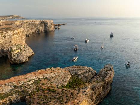 Aerial view of rugged cliffs meet the shimmering turquoise waters of the Blue Lagoon dotted with boats under a clear sky Blue lagoon Comino Malta. Aerial view of rugged cliffs meet the shimmering turquoise waters of the Blue Lagoon dotted with boats under a clear sky Blue lagoon Comino Malta.