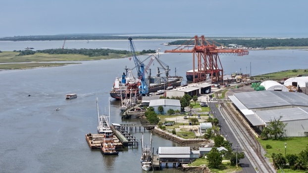 Aerial view of massive orange and blue cranes at a busy port with cargo ships in deep blue waters Fernandina Beach Florida United States. Aerial view of massive orange and blue cranes at a busy port with cargo ships in deep blue waters Fernandina Beach Florida United States.
