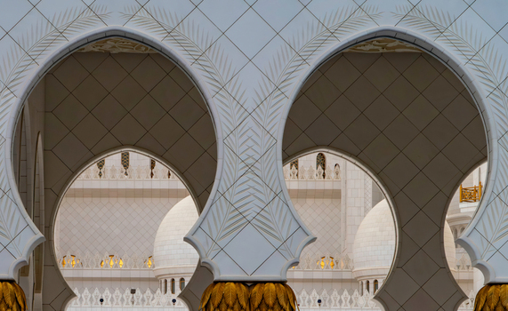 View of ornate white marble arches with gold palm leaf capitals and intricate floral patterns in Abu Dhabi Abu Dhabi United Arab Emirates. View of ornate white marble arches with gold palm leaf capitals and intricate floral patterns in Abu Dhabi Abu Dhabi United Arab Emirates.