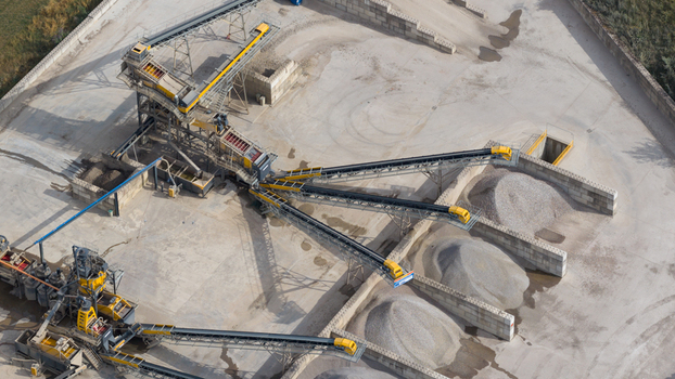 Aerial view of a gravel and sand processing plant featuring industrial machinery conveyor belts and piles of aggregate in La Longueville Hauts de France France.