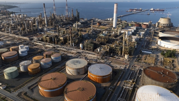 Aerial view of an extensive industrial oil refinery featuring large storage tanks and complex piping systems along the coast Cagliari Sardinia Italy. Aerial view of an extensive industrial oil refinery featuring large storage tanks and complex piping systems along the coast Cagliari Sardinia Italy.