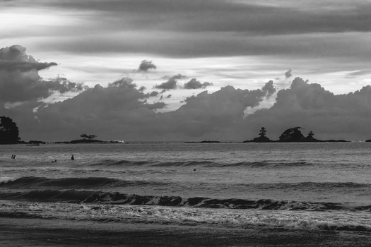 View of the Pacific Ocean coastline with gentle waves distant rocky islets and dramatic clouds over the horizon in Costa Rica.