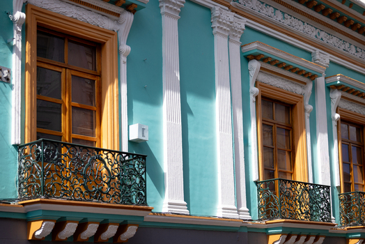 View of the colorful colonial facade in the Historic Center of Quito featuring teal walls white pilasters and ornate wrought iron balconies in Quito Pichincha Ecuador.