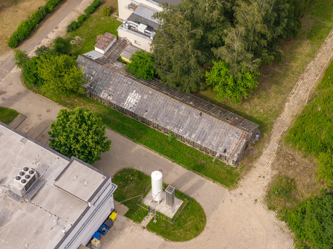 Aerial view of an industrial gas tank and a long glass greenhouse situated near a modern building complex surrounded by trees in Warsaw Masovian Voivodeship Poland. Aerial view of an industrial gas tank and a long glass greenhouse situated near a modern building complex surrounded by trees in Warsaw Masovian Voivodeship Poland.