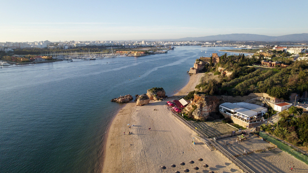 Aerial view of the Ferragudo coastline featuring the historic Castelo de Sao Joao do Arade sandy beaches rocky cliffs and the Arade River estuary in Ferragudo Faro District Portugal.