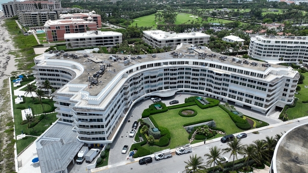 Aerial view of luxurious condos meet the ocean s edge with manicured lawns and a golf course in the distance Palm Beach Florida United States.