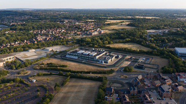 Aerial view of a modern data center facility surrounded by residential housing green fields and trees in Bracknell England United Kingdom.
