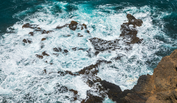 Aerial view of the rugged coastline of Santo Antao with turquoise ocean waves crashing against dark volcanic rocks in Ponta do Sol Ribeira Grande Cabo Verde.