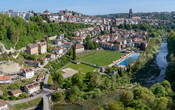 Aerial view of St Nicolas Cathedral overlooking the historic old town a football pitch and the Sarine river in Fribourg Fribourg Switzerland. Aerial view of St Nicolas Cathedral overlooking the historic old town a football pitch and the Sarine river in Fribourg Fribourg Switzerland.