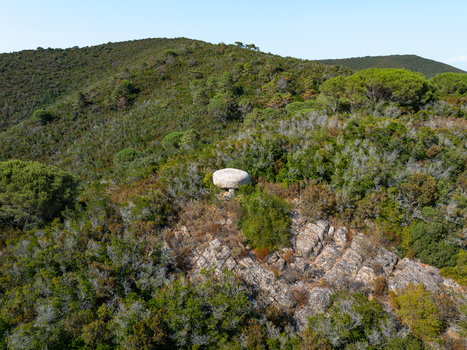 Aerial view of the historic bunker at Passo del Monumento surrounded by dense Mediterranean scrub and rocky terrain in Campo nell Elba Toscana Italy.