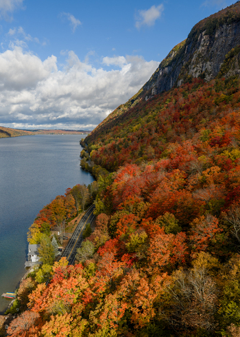 Aerial view of Lake Willoughby surrounded by vibrant autumn foliage on the mountainside with a winding road along the shoreline in Westmore Vermont United States. Aerial view of Lake Willoughby surrounded by vibrant autumn foliage on the mountainside with a winding road along the shoreline in Westmore Vermont United States.