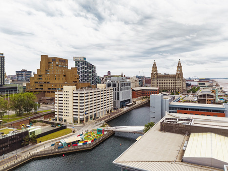 Aerial view of the Liverpool waterfront featuring the historic Royal Liver Building modern architecture and the canal under a cloudy sky in Liverpool England United Kingdom.