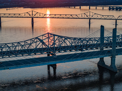 Aerial view of multiple bridges spanning the Ohio River during a golden sunset with sun reflections on the water in Louisville Kentucky United States. Aerial view of multiple bridges spanning the Ohio River during a golden sunset with sun reflections on the water in Louisville Kentucky United States.