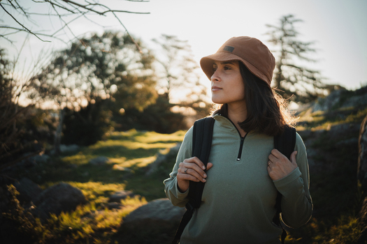 View of a woman trekking in the mountains wearing a bucket hat and backpack during golden hour in Tandil Buenos Aires Argentina. View of a woman trekking in the mountains wearing a bucket hat and backpack during golden hour in Tandil Buenos Aires Argentina.