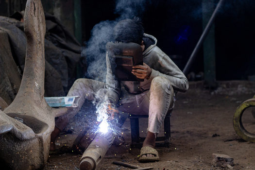 Keraniganj Bangladesh 12 February 2024 View of a worker welding metal parts with bright sparks and smoke at the Shipyard Dhaka.