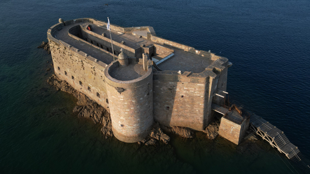 Aerial view of the imposing Ch&acirc;teau du Taureau stands resolute against the deep blue sea its ancient stone walls reflecting the sunlight Plouezoc h Bretagne France.