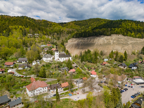 Aerial view of the historic mining village with its white church tower traditional houses and surrounding green hills in Spania Dolina Banska Bystrica Region Slovakia.