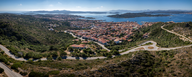 Aerial view of the coastal town of La Maddalena featuring its harbour rooftops and winding roads nestled among Mediterranean hills and blue sea La Maddalena Sardinia Italy. Aerial view of the coastal town of La Maddalena featuring its harbour rooftops and winding roads nestled among Mediterranean hills and blue sea La Maddalena Sardinia Italy.