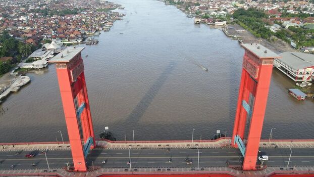 Aerial view of the iconic Ampera Bridge spanning the Musi River with urban development and traffic in the background in Kecamatan Seberang Ulu I Sumatera Selatan Indonesia. Aerial view of the iconic Ampera Bridge spanning the Musi River with urban development and traffic in the background in Kecamatan Seberang Ulu I Sumatera Selatan Indonesia.