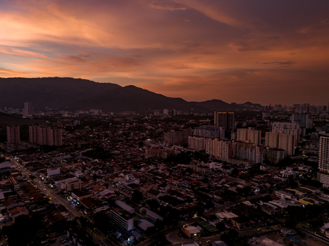 Aerial view of the urban landscape at sunset with residential buildings high rise structures and distant hills under a vibrant orange sky in George Town Penang Malaysia. Aerial view of the urban landscape at sunset with residential buildings high rise structures and distant hills under a vibrant orange sky in George Town Penang Malaysia.
