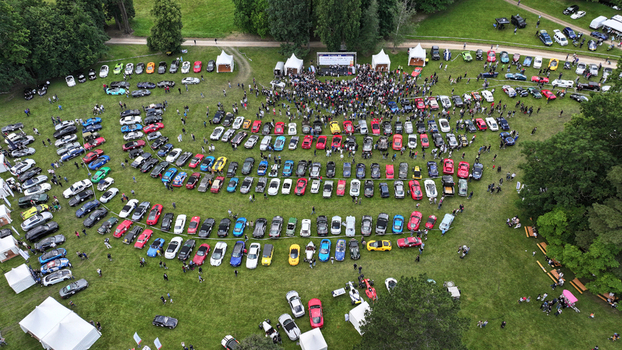 La Chapelle de Guinchay France 01 June 2024 Aerial view of a large gathering of colorful sports cars parked in rows on a green field during a car meet with a crowd of people. La Chapelle de Guinchay France 01 June 2024 Aerial view of a large gathering of colorful sports cars parked in rows on a green field during a car meet with a crowd of people.