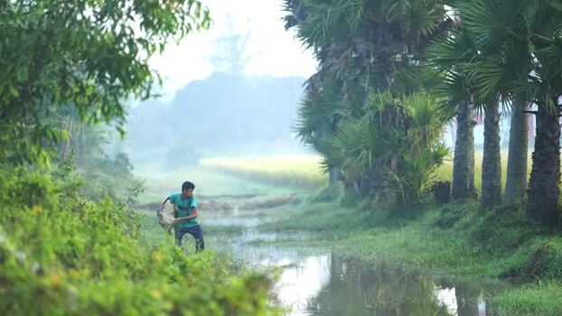 View of a man fishing in a rural stream in Bogura Bangladesh.
