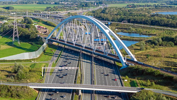 Aerial view of Junction Muiderberg featuring the arched bridge spanning the A1 and A6 motorway interchange with surrounding green landscape in Muiderberg North Holland Netherlands. Aerial view of Junction Muiderberg featuring the arched bridge spanning the A1 and A6 motorway interchange with surrounding green landscape in Muiderberg North Holland Netherlands.