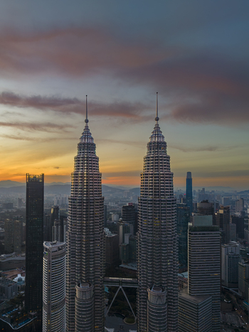 Kuala Lumpur Malaysia 11 March 2026 Aerial view of the Petronas Twin Towers at sunset with the city skyline and colorful clouds in the background.