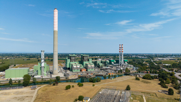 Aerial view of the Tavazzano con Villavesco power station with its tall striped chimney industrial buildings and electrical substation in Tavazzano con Villavesco Lombardy Italy.