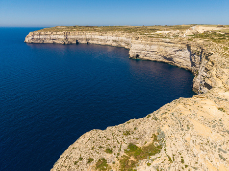 Aerial view of the steep limestone cliffs and deep blue sea at Dwejra Bay in Gozo Region Malta. Aerial view of the steep limestone cliffs and deep blue sea at Dwejra Bay in Gozo Region Malta.