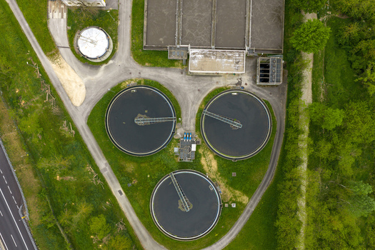 Aerial view of three circular clarifier tanks and rectangular basins of a water treatment facility surrounded by green trees San Giovanni Valdarno Tuscany Italy.