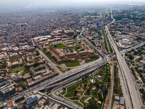 Aerial view of the historic Bala Hisar Fort surrounded by dense urban sprawl major highways and green spaces in Peshawar Khyber Pakhtunkhwa Pakistan.