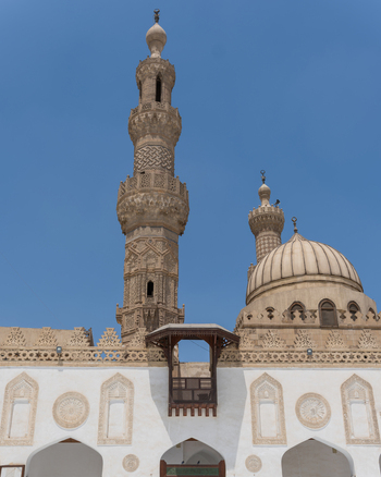 View of Al Azhar Mosque featuring its ornate minarets stone dome and intricate carvings under a clear blue sky in Cairo Egypt. View of Al Azhar Mosque featuring its ornate minarets stone dome and intricate carvings under a clear blue sky in Cairo Egypt.