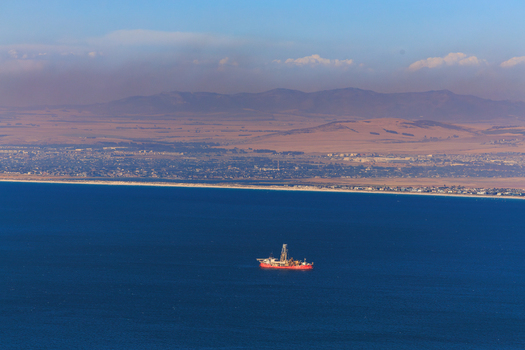 Aerial view of a solitary oil rig stands out against the deep blue ocean contrasted by the distant hazy mountain range Cape Town Western Cape South Africa.