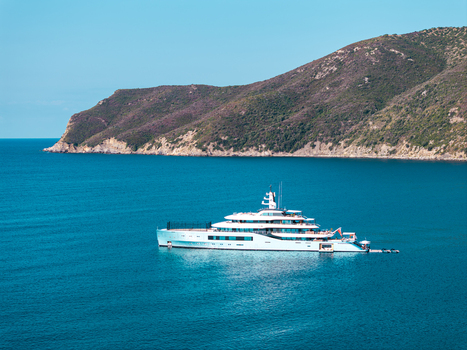 Aerial view of Luxury Yacht Netto II anchored in the calm blue waters of Lacona Bay with the rugged coastline of Elba island in the background Lacona Tuscany Italy.