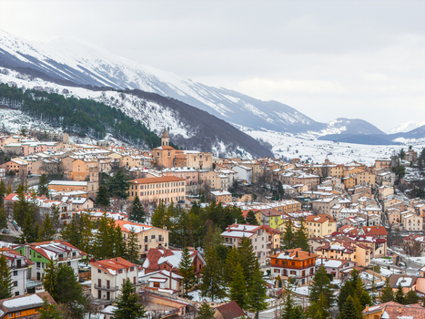 Aerial view of the historic town of Pescocostanzo nestled among snow covered mountains featuring traditional architecture and terracotta rooftops in Pescocostanzo Abruzzo Italy.